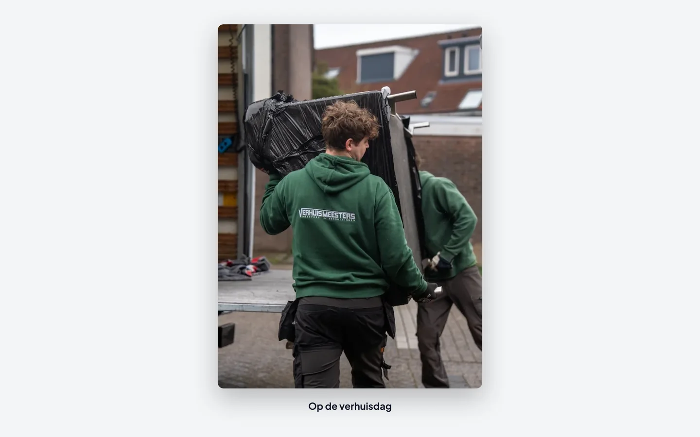 Verhuizers van VerhuisMeesters tillen spullen bij de verhuiswagen voor een woning