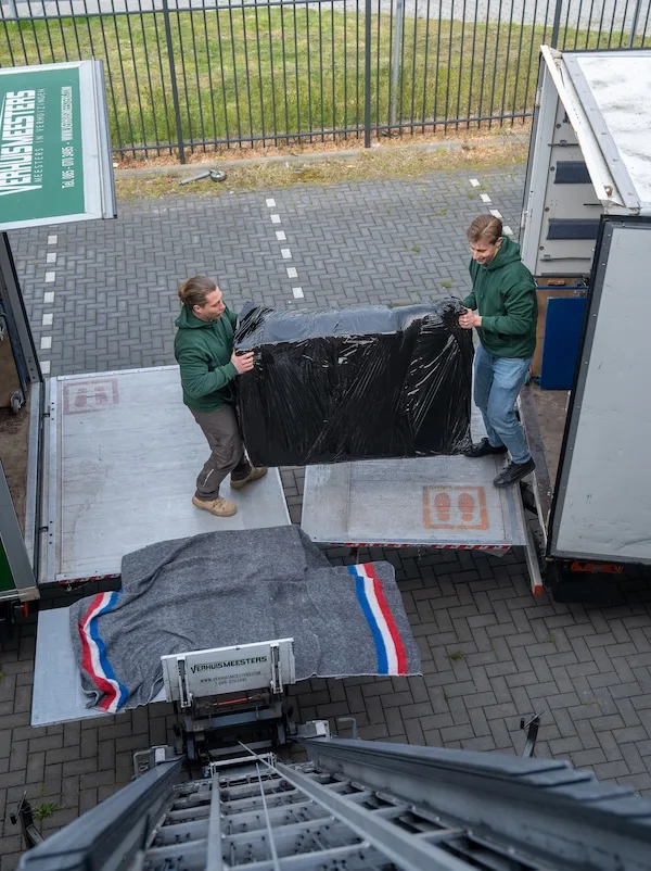 Verhuizer laadt inboedel via de laadklep van de verhuiswagen