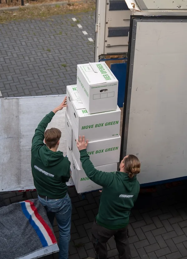 Verhuizers van VerhuisMeesters dragen verhuisdozen naar de wagen