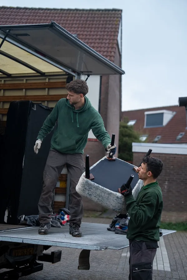 Verhuizer laadt afgevoerde spullen in de wagen