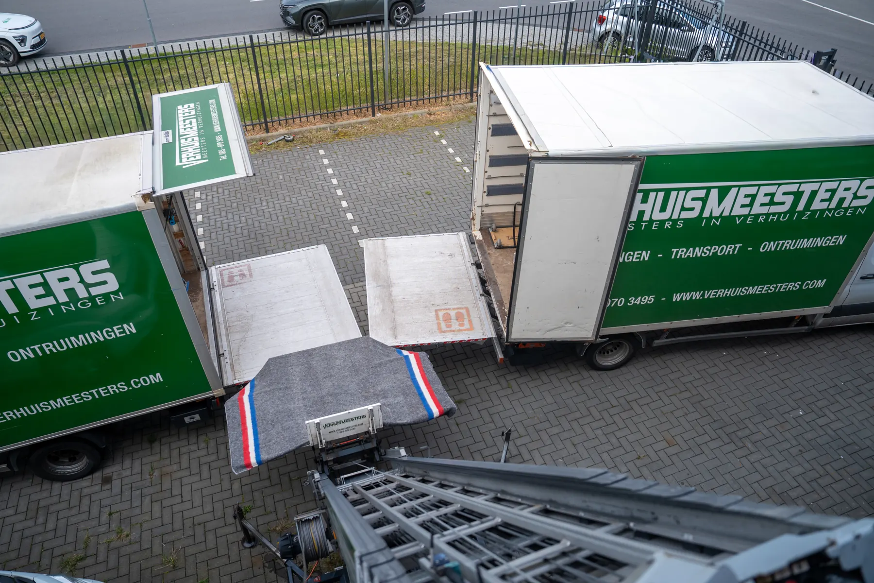Twee verhuiswagens van VerhuisMeesters met laadkleppen en een verhuislift