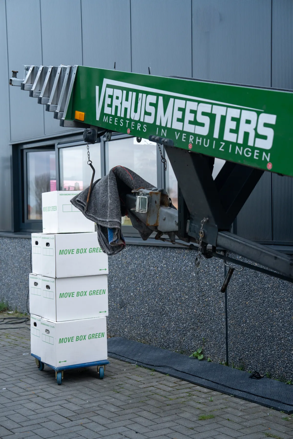 Verhuislift met verhuisdozen bij een bedrijfspand