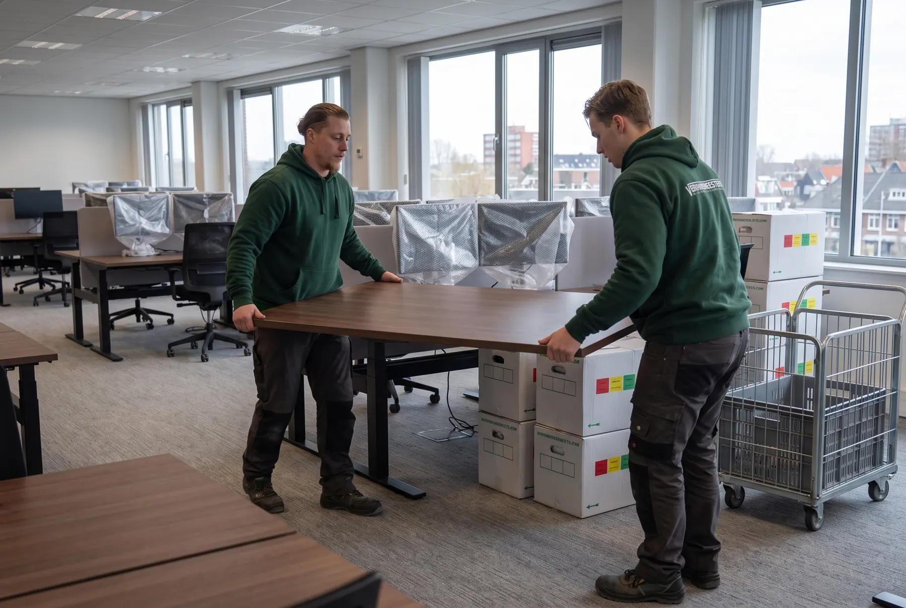 Verhuizers tillen een bureau door een open kantoor met ingepakte beeldschermen